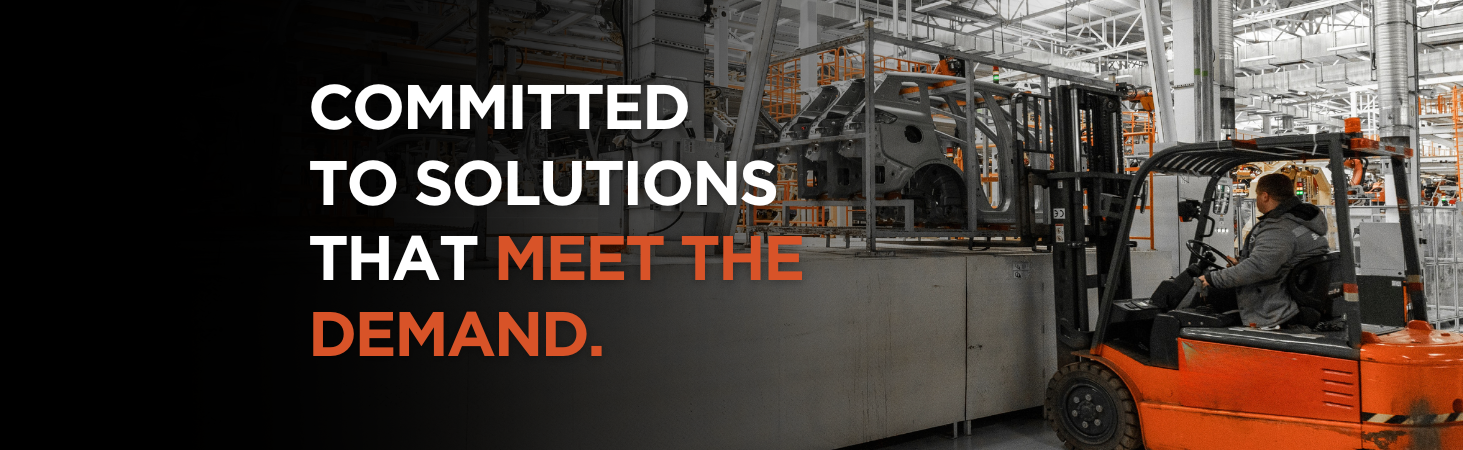 Forklift on automotive assembly line image with caption committed to solutions that meet the demand. Published by Carney Battery Handling